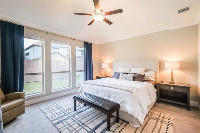 The primary suite is spacious and bright with oversized windows and a ceiling fan. | Image 7