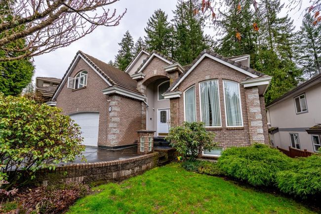 View of front of property featuring a garage, brick siding, a tile roof, a front lawn, and driveway | Image 37