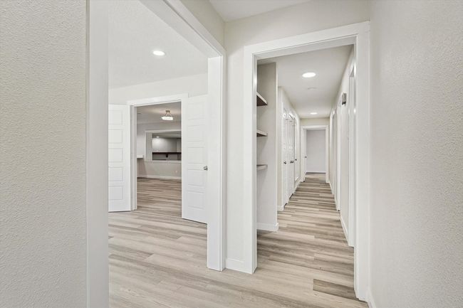 Corridor featuring a textured wall, light wood-type flooring, recessed lighting, and baseboards | Image 16