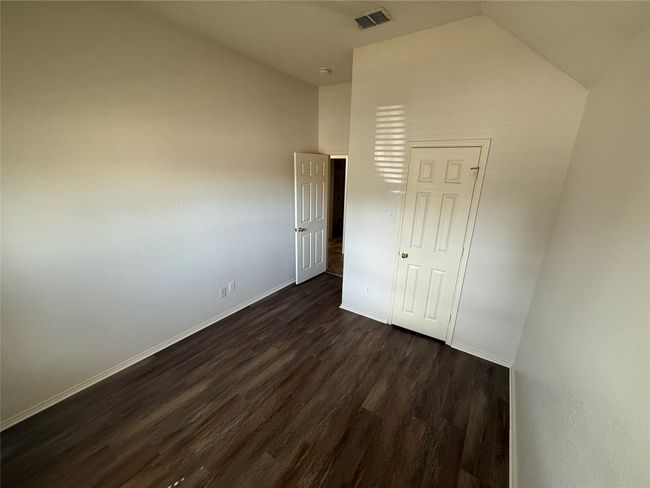 Unfurnished bedroom featuring dark wood-type flooring, lofted ceiling, and baseboards | Image 22