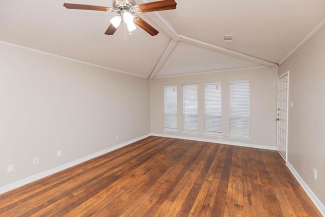 Spare room featuring a ceiling fan, wood-type flooring, baseboards, lofted ceiling, and ornamental molding | Image 6
