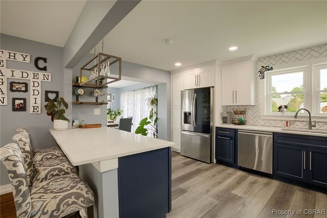 Kitchen with white cabinetry, sink, stainless steel appliances, kitchen peninsula, and a breakfast bar | Image 40