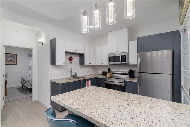 Kitchen with a sink, decorative backsplash, white cabinets, and stainless steel appliances | Image 6