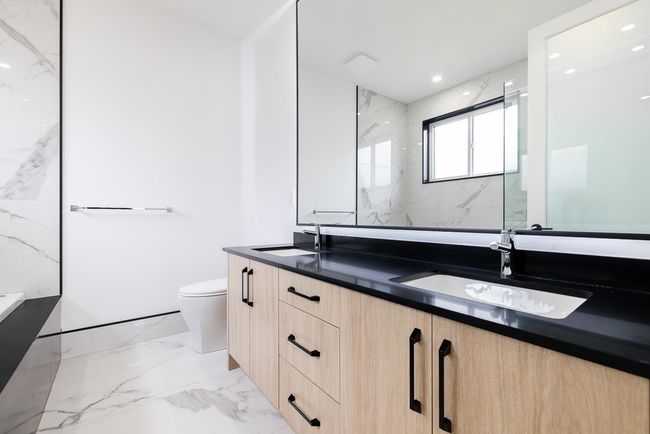 Bathroom featuring double vanity, toilet, marble tiled flooring, and a marble finish shower | Image 29
