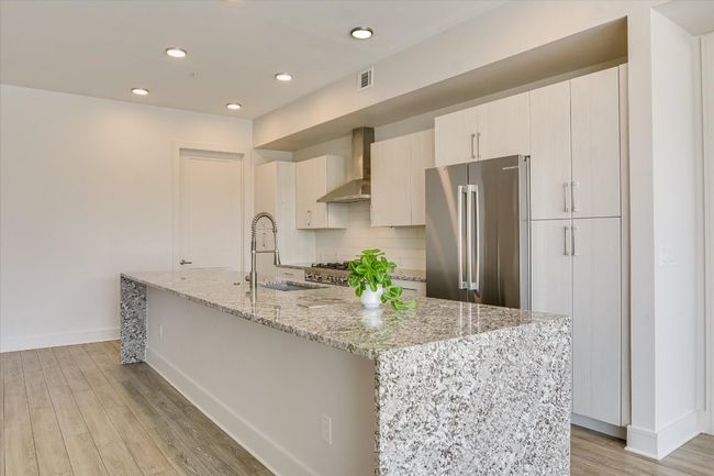 Kitchen with visible vents, freestanding refrigerator, a sink, wall chimney exhaust hood, and tasteful backsplash | Image 7