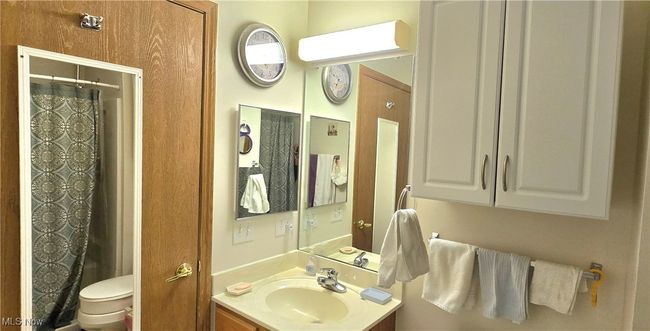 Bathroom with toilet, vanity, and a shower with curtain | Image 24