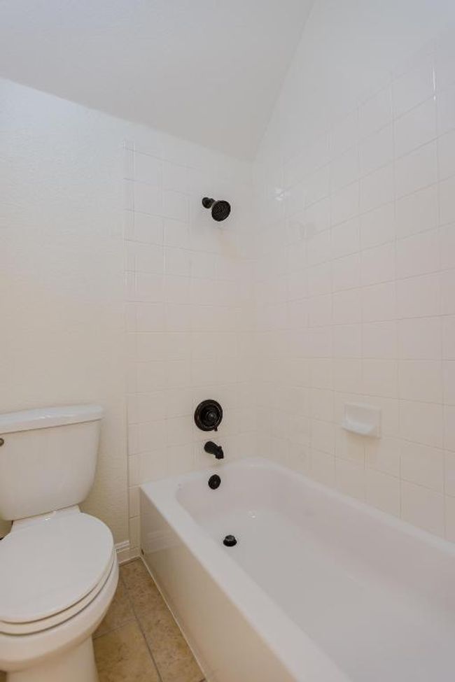 Upstairs Full bathroom featuring tile patterned floors, toilet, shower / bath combination, and lofted ceiling | Image 24
