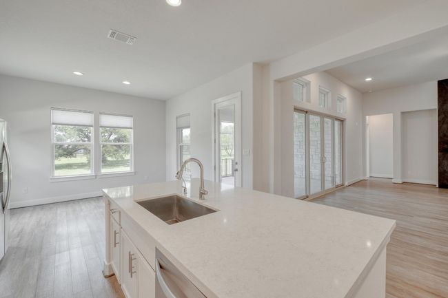 Kitchen featuring light stone counters, light wood-style flooring, recessed lighting, white cabinets, and stainless steel appliances | Image 12