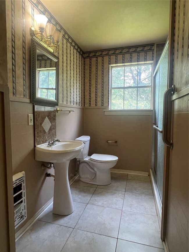 Full bathroom featuring healthy amount of natural light, a stall shower, tile patterned floors, and a wainscoted wall | Image 10