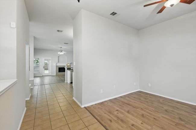 Empty room featuring a ceiling fan, light wood finished floors, and a tiled fireplace | Image 7