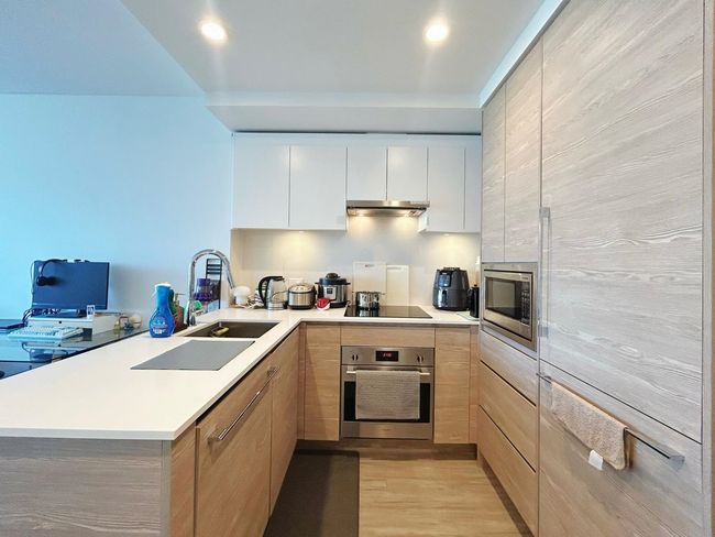 Kitchen featuring stainless steel appliances, a sink, modern cabinets, light wood-style floors, and light countertops | Image 6