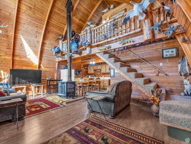 Living room with wooden walls, high vaulted ceiling, a wood stove, hardwood / wood-style floors, and a wooden ceiling with exposed beams | Image 5