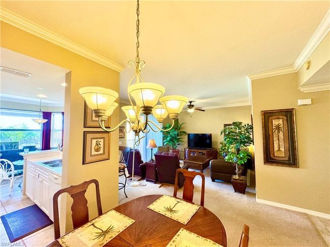 Dining area featuring visible vents, baseboards, a chandelier, light colored carpet, and ornamental molding | Image 13