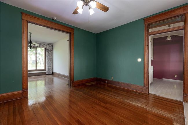 Unfurnished room featuring ceiling fan with notable chandelier and hardwood / wood-style floors | Image 7