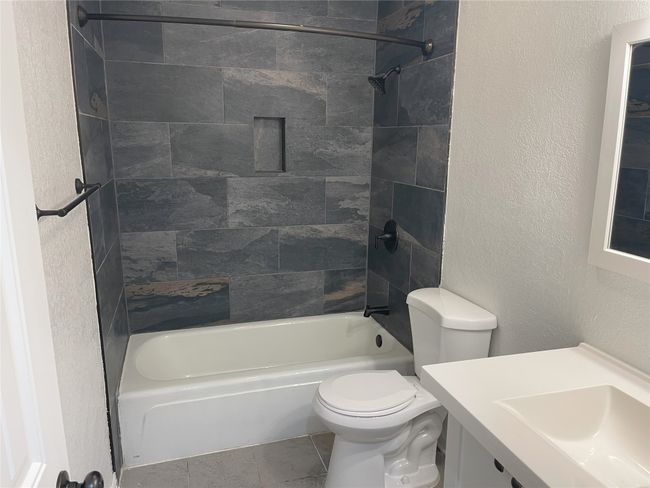 Full bath featuring bathing tub / shower combination, vanity, and a textured wall | Image 13