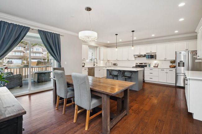 Dining space with dark wood-type flooring, a chandelier, ornamental molding, and recessed lighting | Image 9