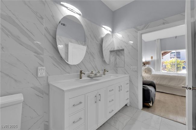 Full bathroom featuring tile walls, double vanity, connected bathroom, and marble finish floors | Image 31
