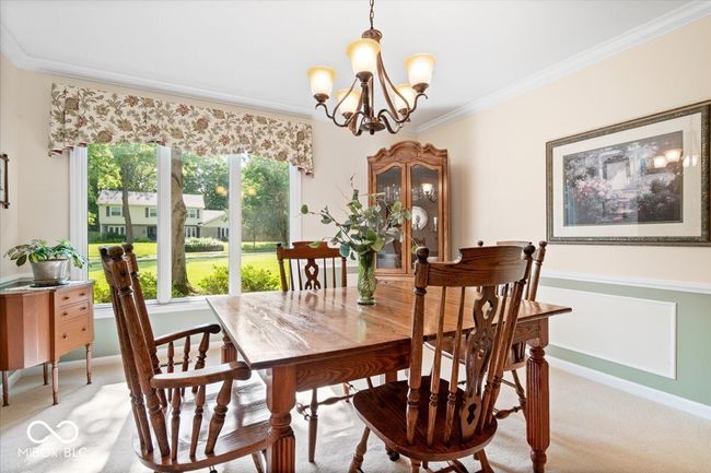 dining room featuring light carpet, a chandelier, and ornamental molding | Image 17