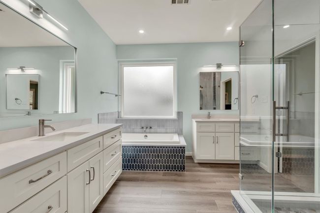 Full bathroom featuring wood finished floors, a sink, a stall shower, two vanities, and visible vents | Image 10