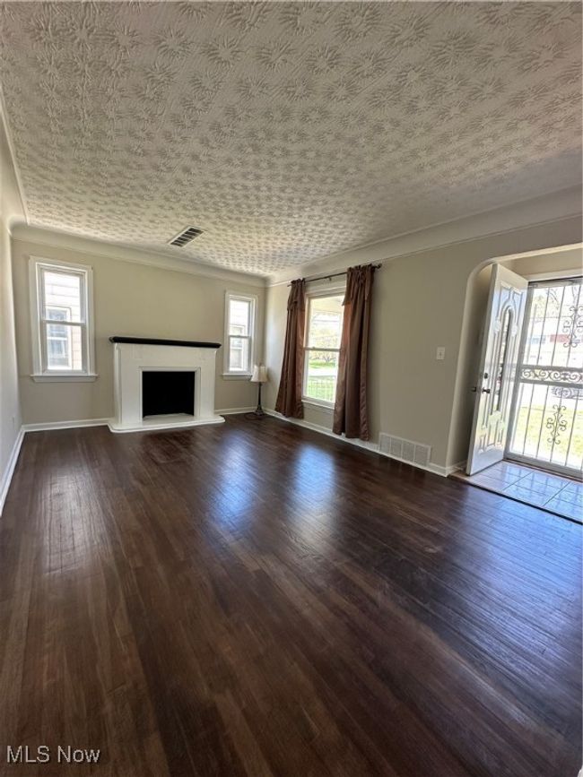 Unfurnished living room with dark wood finished floors, visible vents, arched walkways, and baseboards | Image 18