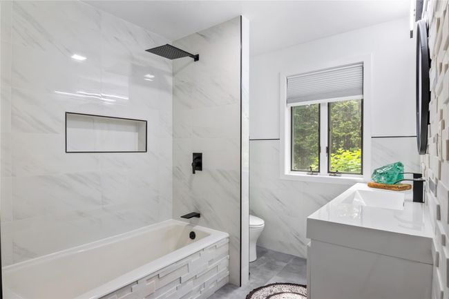 Bathroom featuring vanity, toilet, washtub / shower combination, and tile walls | Image 21