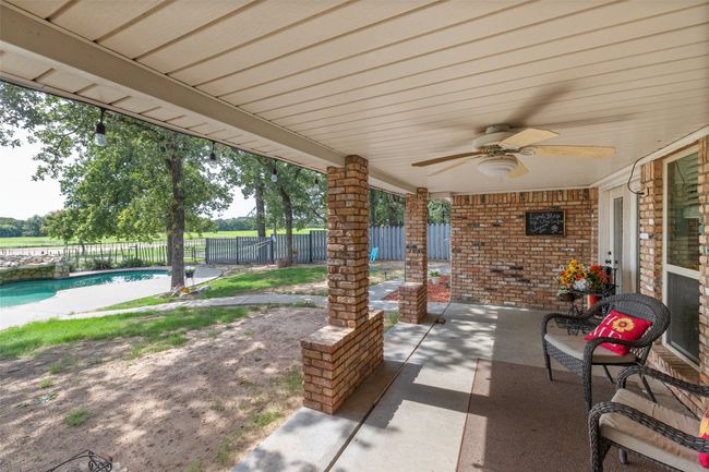 View of patio with fence, a ceiling fan, and a fenced in pool | Image 35