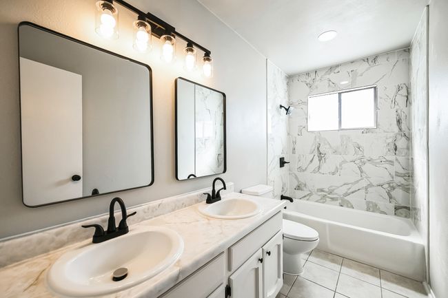 Full bathroom featuring double vanity, tile patterned flooring, toilet, and a sink | Image 12