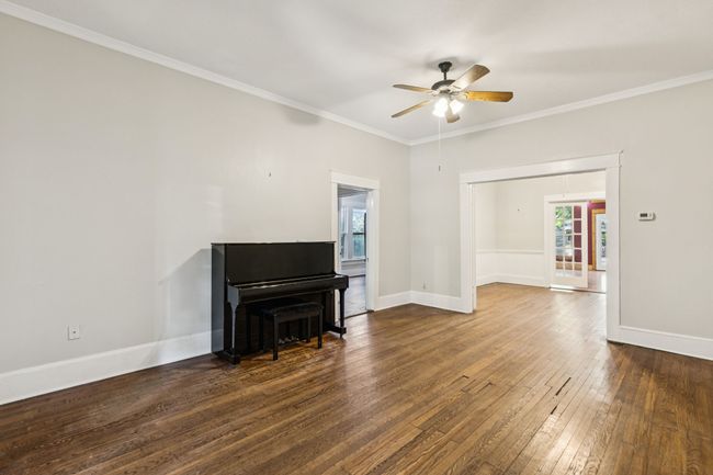 Living area featuring dark wood finished floors, ceiling fan, crown molding, and baseboards | Image 4