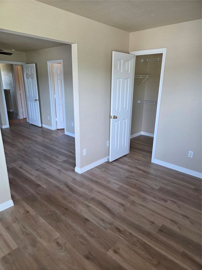 Unfurnished bedroom featuring dark wood-style floors, a spacious closet, and a closet | Image 29