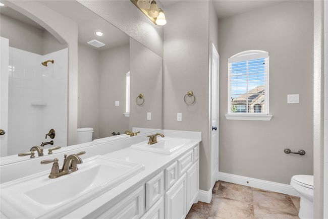 Full bath featuring toilet, baseboards, a shower, and double vanity | Image 23