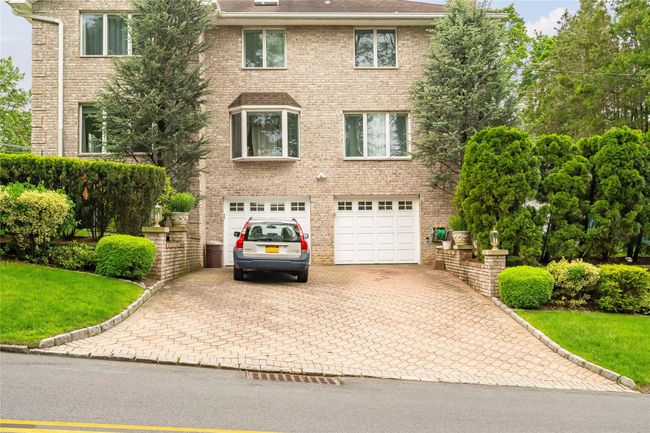 Colonial house with decorative driveway, an attached garage, brick siding, and a front yard | Image 45