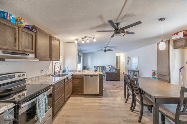 Kitchen with a ceiling fan, under cabinet range hood, a sink, stainless steel appliances, and a peninsula | Image 22