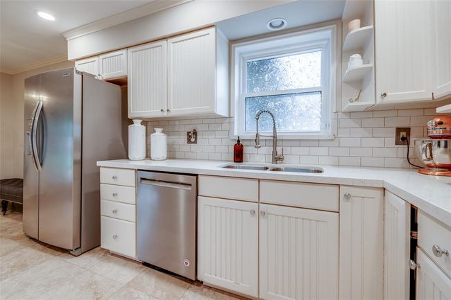 Spacious kitchen with white cabinets, white subway tiled back splash, travertine tiled floor, Kitchen Aid Gas cook top & Kitchen Aid single Oven, vent, pantry, refrigerator included in the sales price, recessed lighting | Image 16