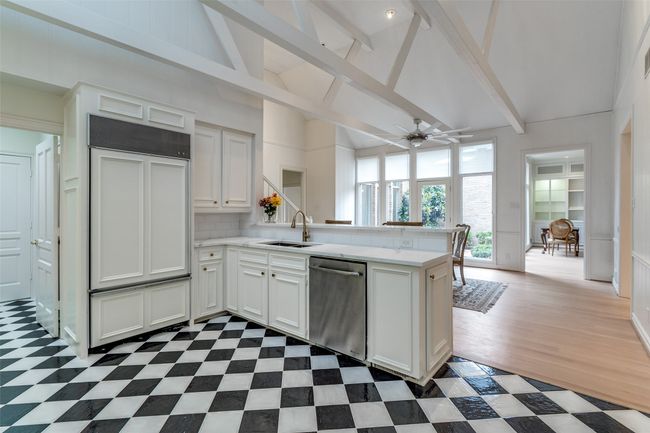 Kitchen with stainless steel dishwasher, a peninsula, a sink, light countertops, and high vaulted ceiling | Image 9
