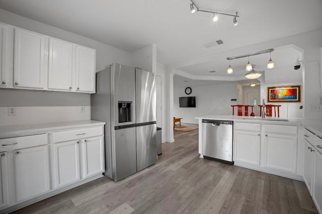 Kitchen featuring appliances with stainless steel finishes, rail lighting, light wood-type flooring, white cabinetry, and light countertops | Image 8