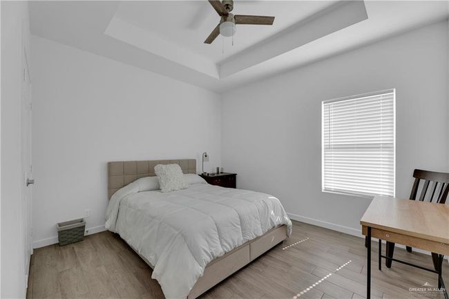 Bedroom featuring ceiling fan, light wood-type flooring, and a tray ceiling | Image 18