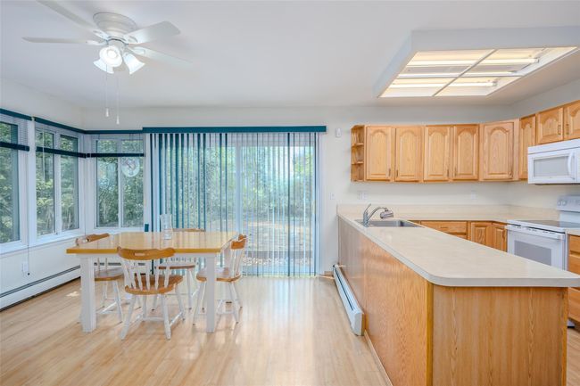 Dining space with a baseboard heating unit, light wood-style flooring, and ceiling fan | Image 15