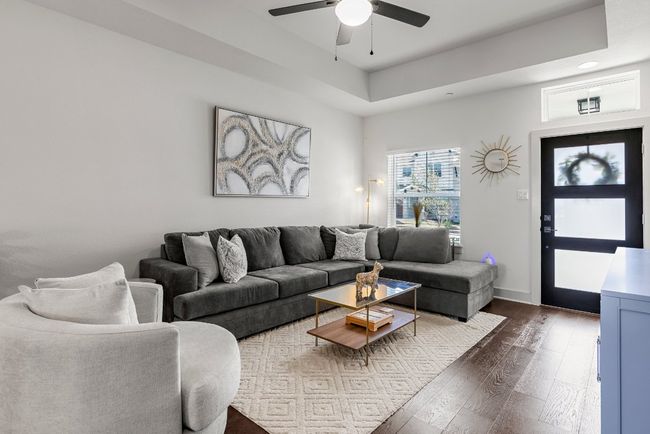 Another view of the charming living room, featuring high ceilings and warm wood floors. | Image 7