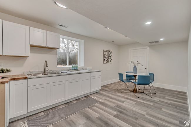 Kitchen with white cabinets, light wood-style floors, visible vents, and a sink | Image 16