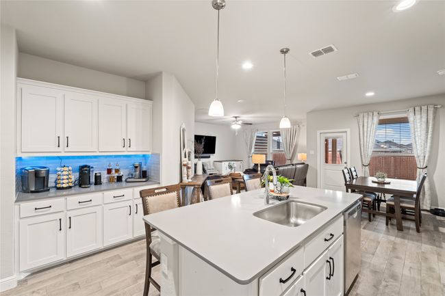 Kitchen with visible vents, light wood-style flooring, a sink, stainless steel dishwasher, and decorative backsplash | Image 12