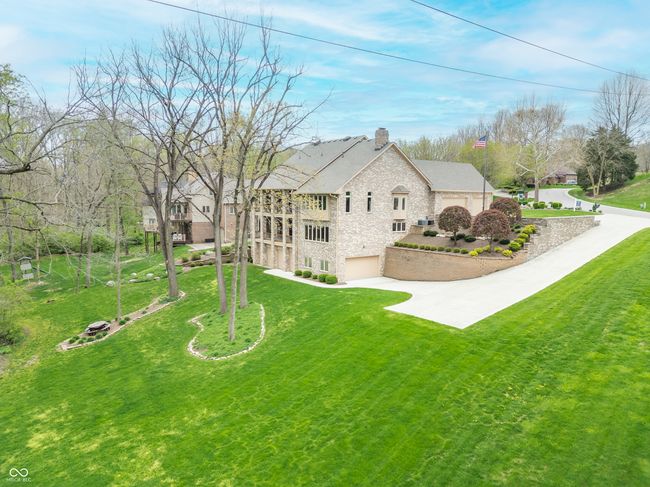 exterior space featuring a chimney, a yard, stone siding, concrete driveway, and an attached garage | Image 111