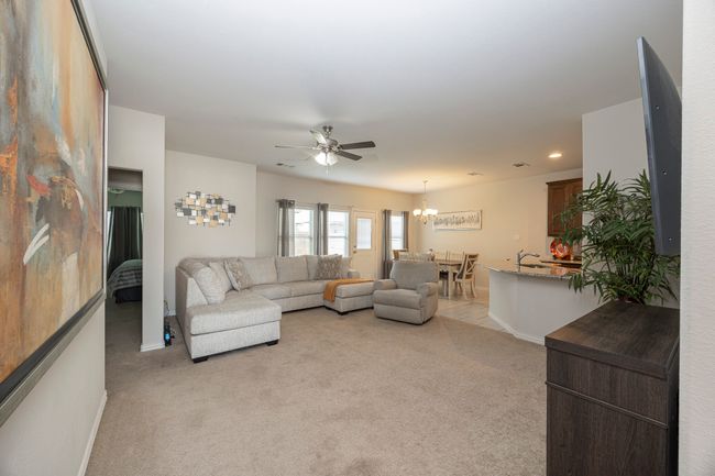 Living area featuring light colored carpet, a ceiling fan, a chandelier, and recessed lighting | Image 11