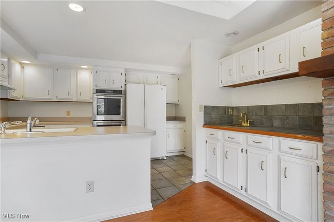 Kitchen featuring white cabinets, freestanding refrigerator, double oven, and a sink | Image 21