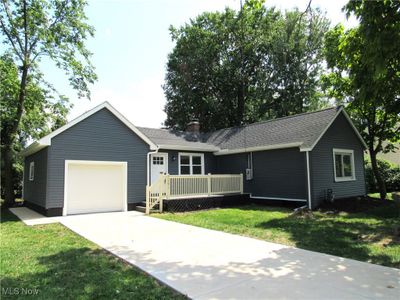 Ranch-style home featuring a front yard and a garage | Image 1