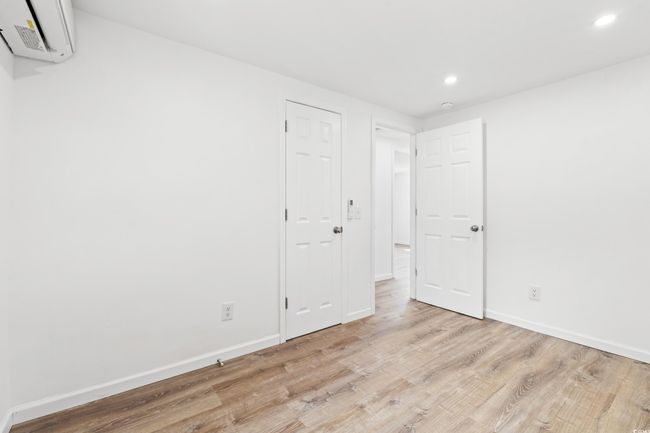 Unfurnished room featuring recessed lighting, wood finished floors, baseboards, and a wall unit AC | Image 11