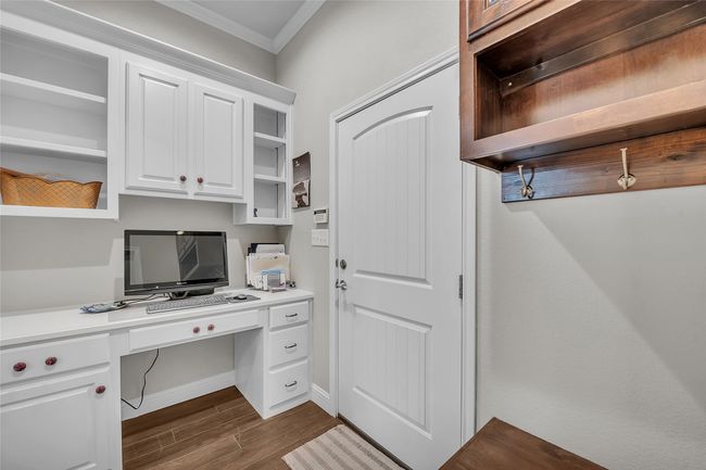 Unfurnished office with ornamental molding, built in desk, and dark wood-type flooring | Image 22