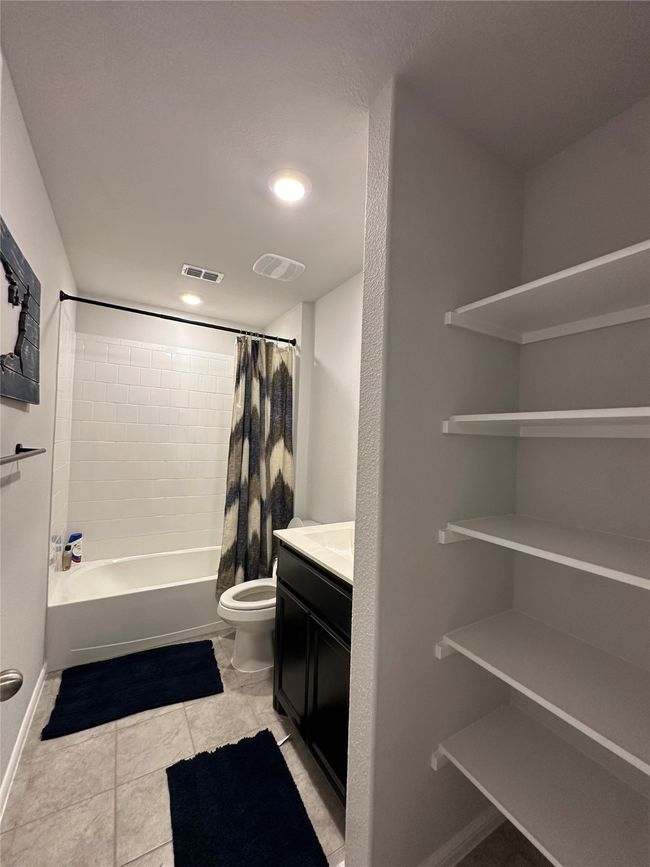 Bathroom with shower / bath combination with curtain, vanity, tile patterned floors, and visible vents | Image 17