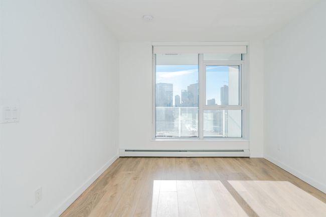 Unfurnished room featuring light wood-style flooring, a view of city, a baseboard heating unit, and baseboards | Image 21