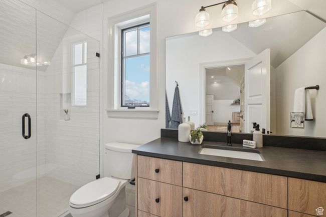 Bathroom featuring lofted ceiling, a stall shower, vanity, and toilet | Image 38