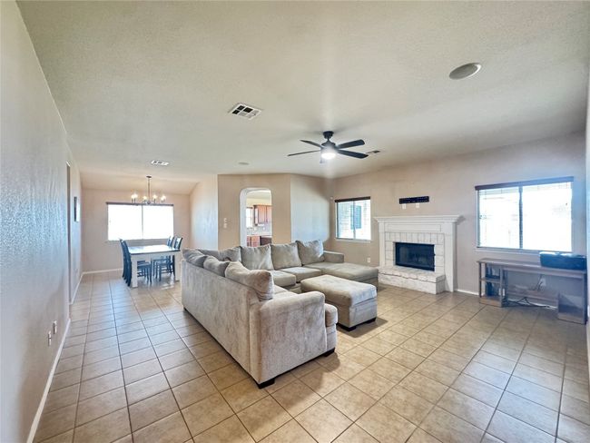 Living room featuring light tile patterned floors, a chandelier, a stone fireplace, plenty of natural light, and a textured ceiling | Image 6